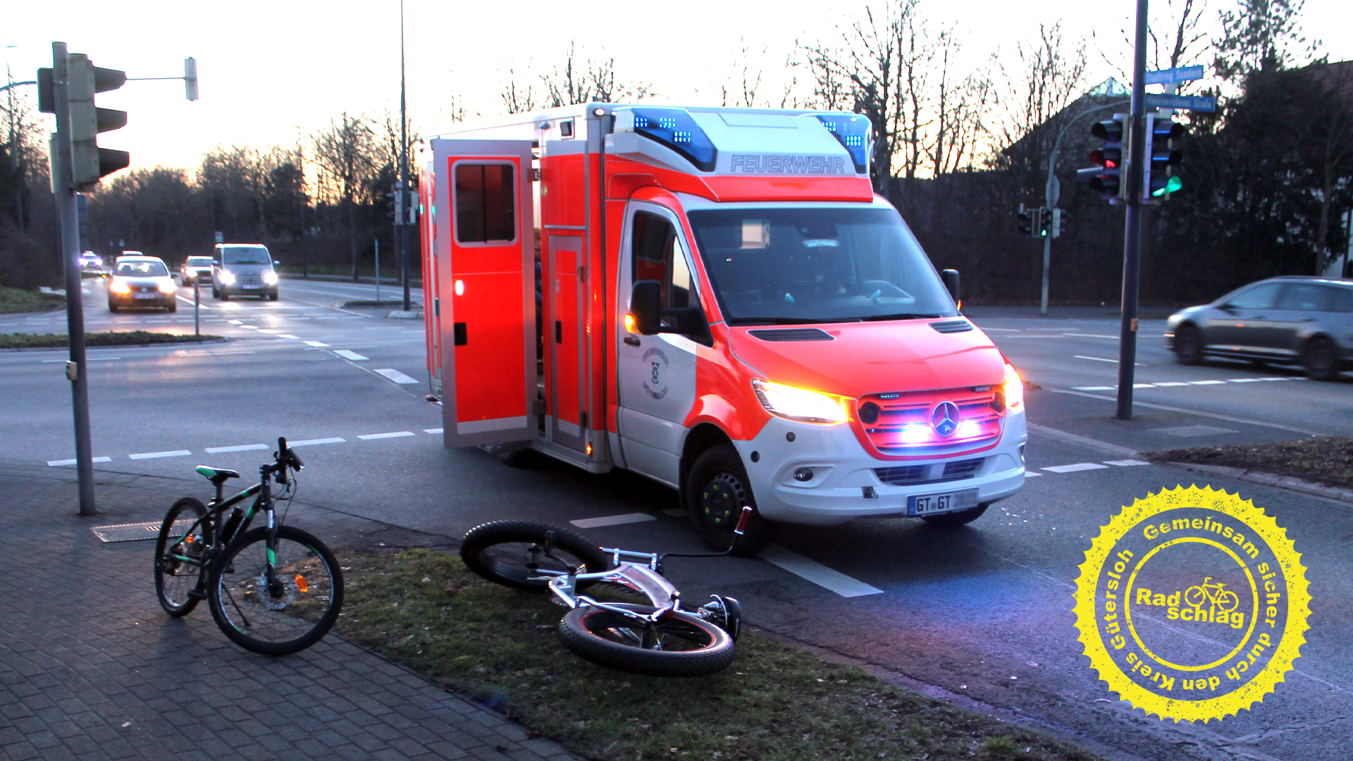 Ein Rettungswagen an einer Kreuzung, daneben liegt ein Fahrrad auf dem Grünstreifen