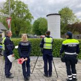 Drei Polizisten und eine Polizistin von hinten zu sehen an einer Kontrollstelle