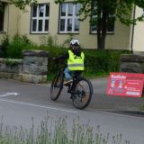 Ein Junge fährt auf dem Fahrrad über einen Schulhof an einem Schild mit der Aufschrift Radfahrprüfung vorbei