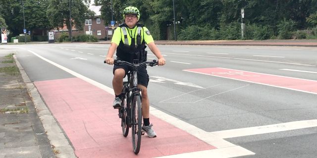 Polizeihauptkommissar steht mit seinem Fahrrad auf der Aufstellfläche und blickt Richtung Ampel