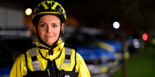 Polizeikommissarin Katharina Philippi ist in Großaufnahme zu sehen. Sie trägt eine Fahrraduniform mit Fahrradhelm. 