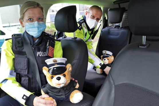 Eine Polizistin und ein Polizist mit zwei Polizeiteddybären
