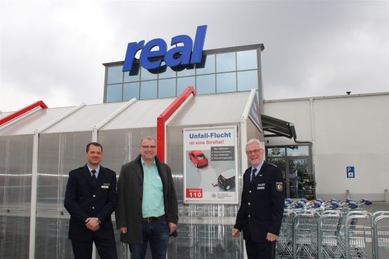 Leitender Polizeidirektor Christoph Ingenohl, Polizeihauptkommissar Heiko Patzelt und den Geschäftsleiter des Real-Marktes, Herrn Eschweiler beim Aufhängen der Plakate auf dem Parkplatz des Marktes an der Straße Am Anger in Gütersloh.